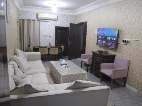 a living room with white furniture and a tv at العين الهيلي مصباح ب 2 in Al Ain