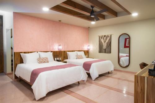 een slaapkamer met twee bedden en een spiegel bij Luuna de Jade in Oaxaca City