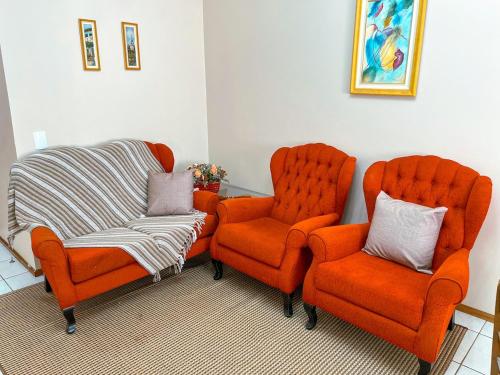 two orange chairs and a couch in a room at Rua Capitao Eleuterio, 210 - Centro · SI Belo Apto – Próx. HSVP e Hospital de Clínicas in Passo Fundo