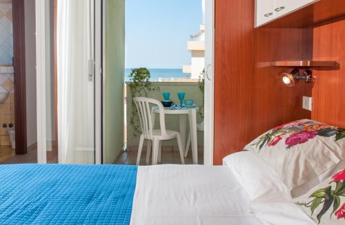 a bedroom with a bed and a balcony with a table at Residence Nautic in Rimini