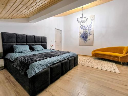 a bedroom with a large black bed and a couch at Casa Runcu Dambovita in Bădeni