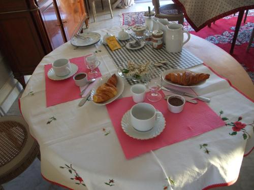 un tavolo con una tovaglia bianca con croissant e tazze di il giardino F Heudier ,E Decourcy ,Tessy sur vire Manche a Tessy-sur-Vire