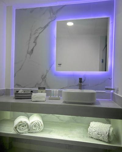 a bathroom with a sink and a mirror and towels at Valle de Santiago Hotel Boutique in San Cristóbal