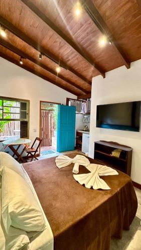 a bedroom with a large bed with a flat screen tv at Chalés Água Grande in Maresias