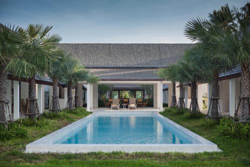 una piscina frente a una casa con palmeras en Villa Aditi - Amazing Beachfront Villa, en Nathon Bay