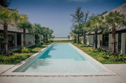 una piscina frente a una casa con palmeras en Villa Aditi - Amazing Beachfront Villa, en Nathon Bay