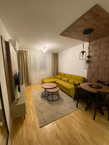 a living room with a yellow couch and a table at Diva apartman in Donje Mladice