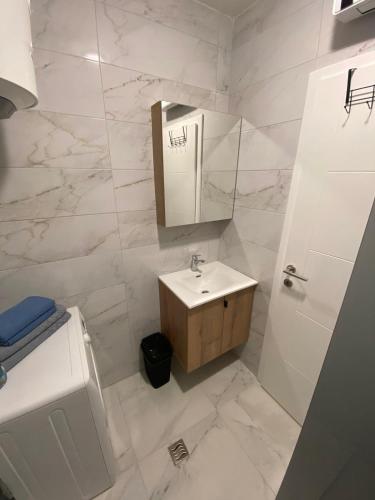 a white bathroom with a sink and a mirror at Diva apartman in Donje Mladice