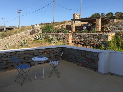 two chairs and a table on a patio with a stone wall at Villa Aqua Marina in Vourkarion