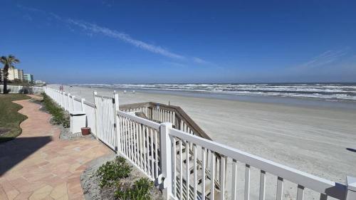 a white fence next to a beach with the ocean at Magnificent Beach Front Condo - Flagler Ave - 111 in New Smyrna Beach
