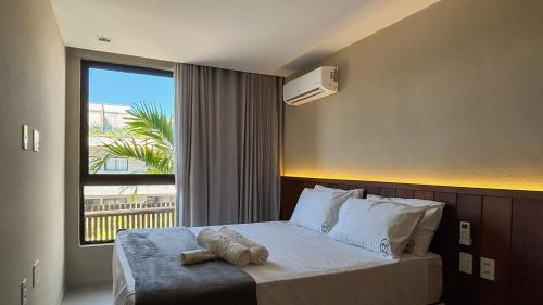 ein Schlafzimmer mit einem Bett mit einem großen Fenster in der Unterkunft Casa 3 Suítes Piscina e Hidro para até 9 pessoas in Tatuamunha