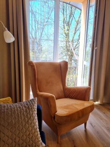 a brown chair sitting in front of a large window at Akacja Centrum Apartament in Rzeszów