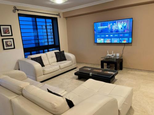 a living room with two white couches and a flat screen tv at Terraza del Sol in Macuto