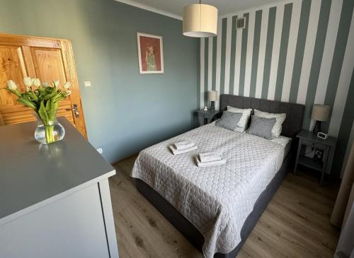 a bedroom with a bed with a vase of flowers on it at Apartament Akacja CENTRUM in Rzeszów