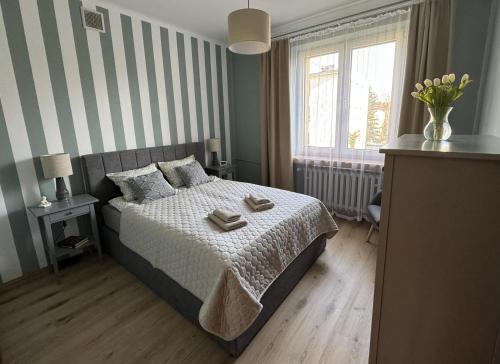 a bedroom with a bed with a striped wall at Apartament Akacja CENTRUM in Rzeszów