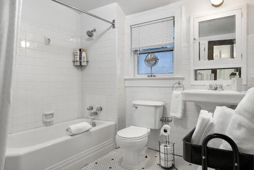 a white bathroom with a toilet and a tub and a sink at Southern Tides- Pool, Fire Pit & Games in Birmingham