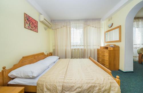 a bedroom with a bed and a dresser and a window at Hotel Druzhba in Kyiv