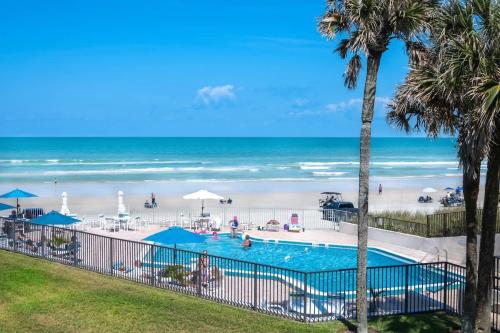 a swimming pool next to a beach with the ocean at Gorgeous Beach Front Condo Near Flagler Ave - 701 in New Smyrna Beach
