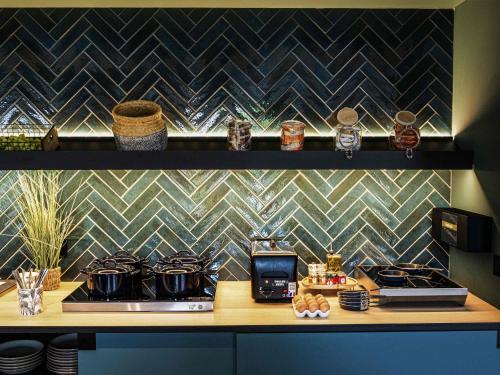 Una cocina con una encimera con estufa y algunas ollas y sartenes. en Novotel Lens Noyelles, en Noyelles-Godault