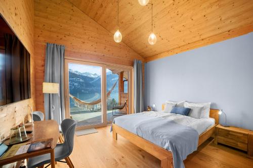 a bedroom with a bed and a large window at Chalet Diognysos B&B, Boutique Hotel & Wellness in Crans-Montana