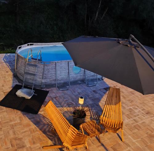 an umbrella and chairs next to a swimming pool at Apartma Ariana in Loče pri Poljčanah
