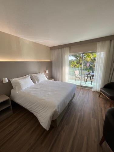 a bedroom with a large white bed and a patio at Hotel Mirante São Brás in São Brás do Suaçuí