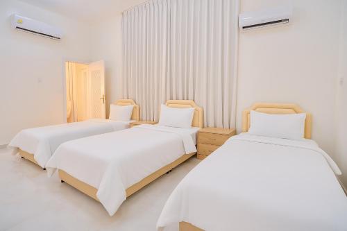Dos camas en una habitación con paredes blancas. en Remal Chalet, en Badīyah