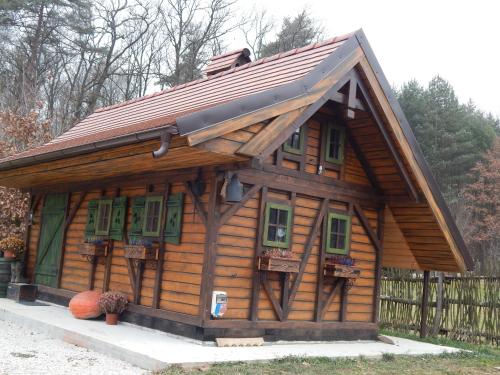 a small log cabin with green windows and a roof at Chata Bavor Látkovce in Uhrovec