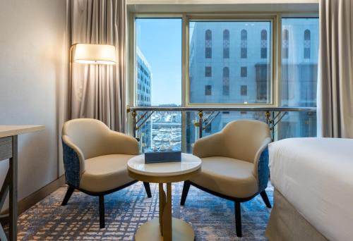 a hotel room with a bed and two chairs and a window at MADEN Al Rawda مادن الروضة in Medina