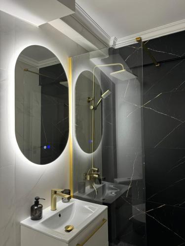 a bathroom with a sink and two mirrors at Cuza Residence in Craiova