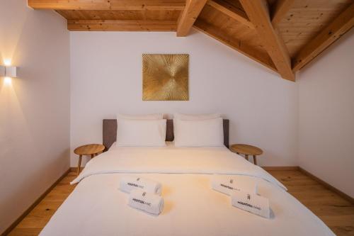 a bedroom with a bed with white sheets and wooden ceilings at Tagenhof Mountain Living in Meluno