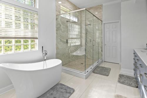 a white bathroom with a tub and a shower at Riverfront Escape! Private Pier, 4 BR Home and Room to Entertain in Jacksonville