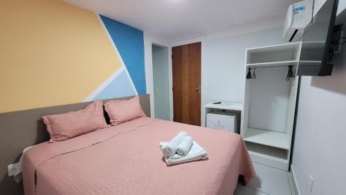 a small bedroom with a pink bed with pink pillows at Pousada Sol e Descanso by Easy Hotéis in Arraial do Cabo