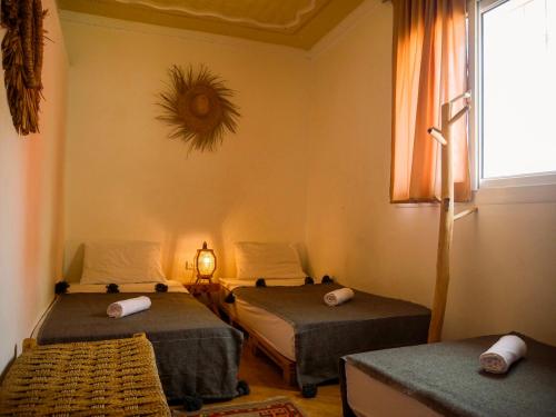 una habitación con dos camas y una ventana en caban surf Tamraght, en Tamraght Ouzdar