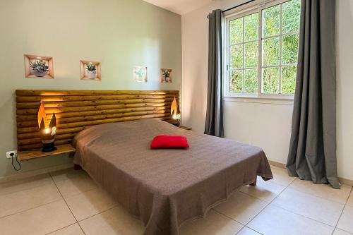a bedroom with a bed with a red pillow on it at Perle d'Arlet in Les Anses-dʼArlets
