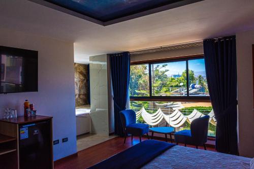 a bedroom with a large window with chairs and a table at Hotel Terra by Refugio Ecológico in Arequipa
