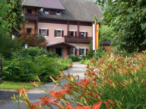 a house with a garden with flowers in front of it at Georgihof im Park in Unterburg am Klopeiner See
