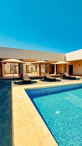 a swimming pool with chairs and umbrellas next to a building at Finca el Cielo San Carlos Sonora in San Carlos