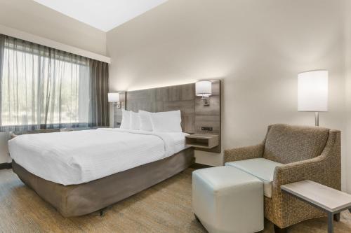 a hotel room with a large bed and a chair at Best Western Plus Executive Residency Phoenix North Happy Valley in Phoenix