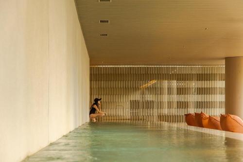 a woman sitting in the water in a swimming pool at Pulso Hotel Faria Lima in Sao Paulo