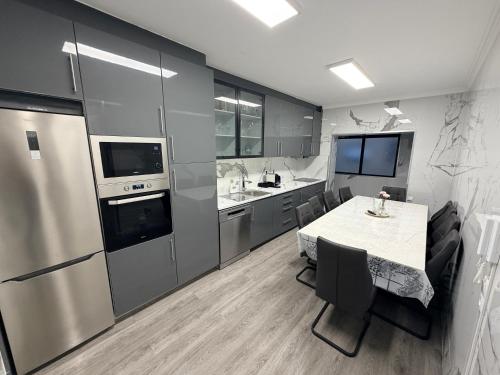 a kitchen with a table and a sink and a refrigerator at Spacieux appartement 3 chambres à 200 m de la plage in Ovar