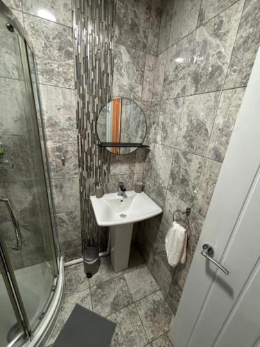 a bathroom with a sink and a mirror and a shower at Court Studio Apartment in Cardiff