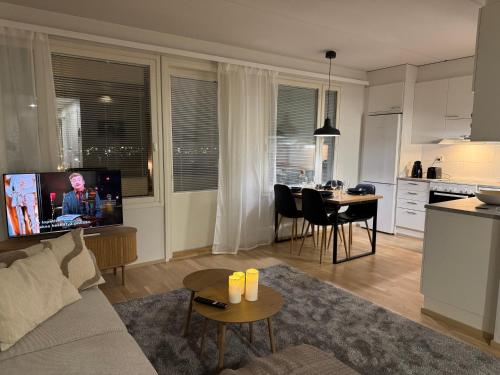 a living room with a couch and a table and a kitchen at Lapland Apartments with private sauna, wifi and parking next to the railway station in Rovaniemi