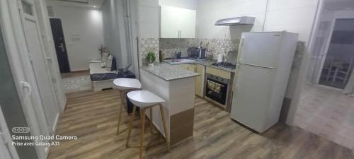 a kitchen with a white refrigerator and two stools at Douera good f2 in Douera