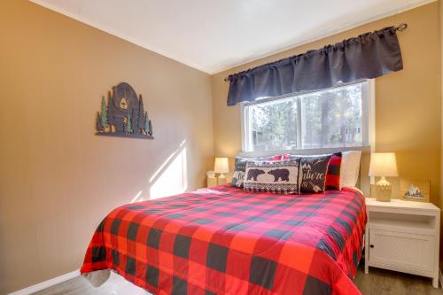 ein Schlafzimmer mit einem Bett mit einer karierten Decke und einem Fenster in der Unterkunft Big Bear Ski Hideaway! Cozy Cabin with Fenced Yard in Big Bear City Airport
