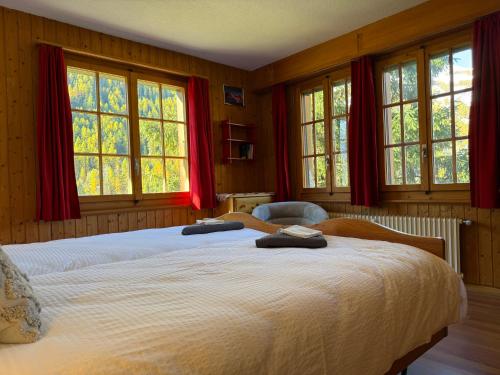 a bedroom with two beds with red curtains and windows at Appartement Églantier in Evolène