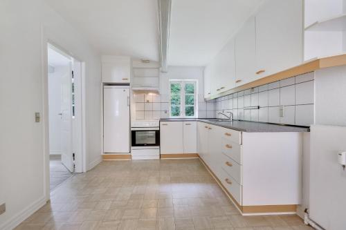 a white kitchen with white cabinets and a tile floor at Annexgården 9A in Tommerup