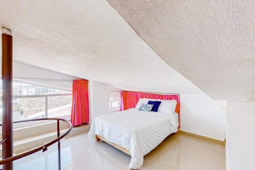 a white bedroom with a bed and a window at Torre Malibu, Loft # 805 in Puerto Vallarta