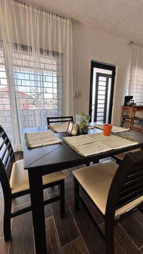 a dining room with a table and chairs and windows at Departamento moderno con wifi y AC in Ciudad del Carmen