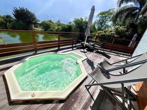 a hot tub on a deck with a chair and an umbrella at BUNGA-LODGE (bungalow 4* avec piscine privée) in Douville